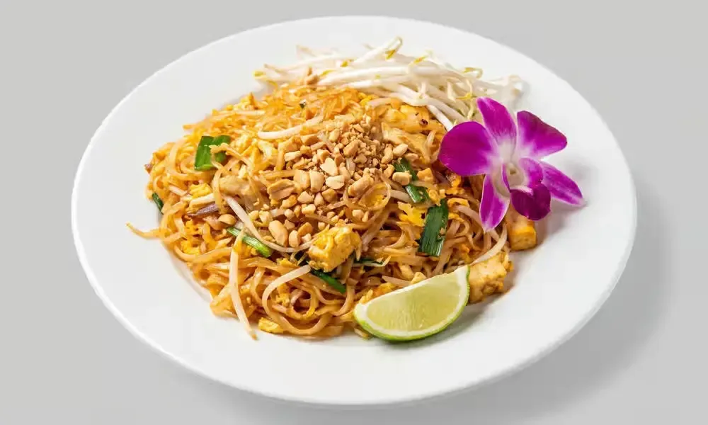 Sweet Rice Pad Thai topped with peanuts and served with lime